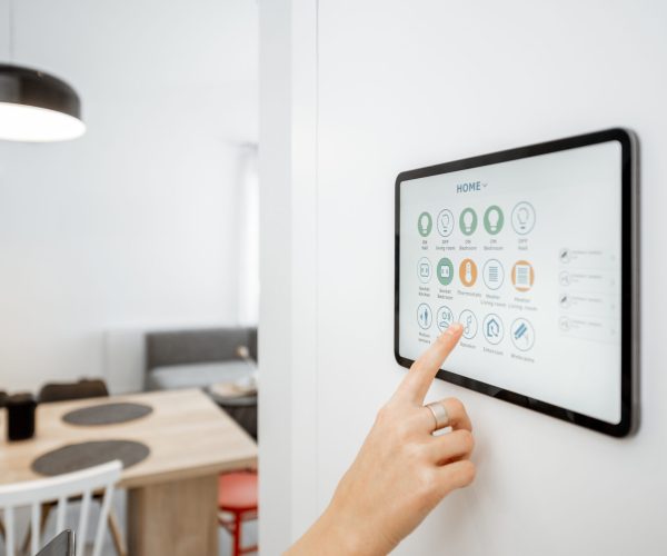 Controlling home with a digital touch screen panel installed on the wall. Close-up on a screen with mobile application for managing smart devices